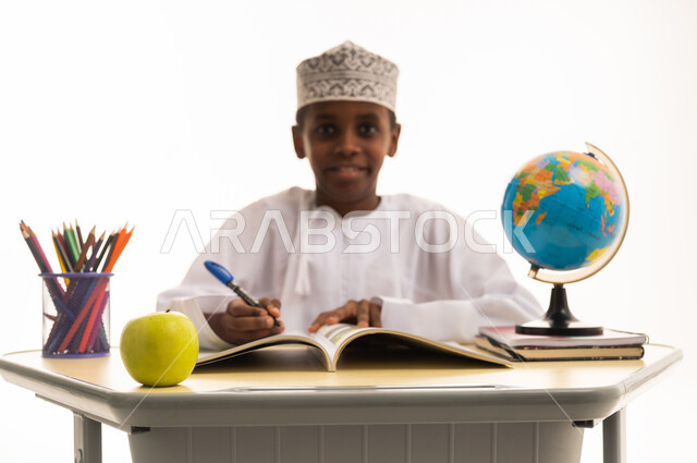 طالب عماني يكتب على المكتب مع كرة أرضية