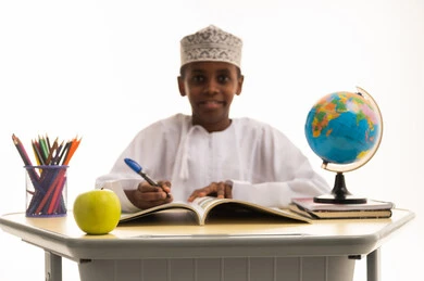 طالب عماني يكتب على المكتب مع كرة أرضية طالب عماني يكتب على المكتب مع كرة أرضية