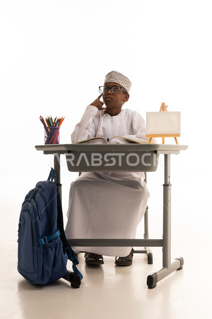طالب عماني يفكر خلف مقعده الدراسي بخلفية بيضاء