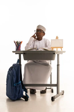 طالب عماني يفكر خلف مقعده الدراسي بخلفية بيضاء