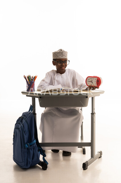 Omani Student at School Desk with Alarm Clock