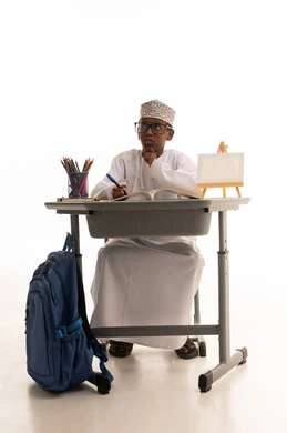 Omani Student at Desk with Traditional Dishdasha