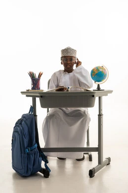 طالب عماني خلف مقعد دراسي مع حقيبة مدرسة