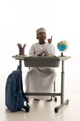 طالب عماني يجلس على مكتب دراسي ويشير للأعلى