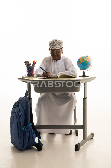 Omani Student Writing at School Desk with Globe