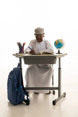 طالب مدرسي عماني يكتب على المكتب مع كرة أرضية