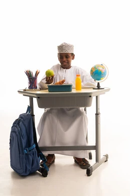 طالب مدرسي عماني على مقعد الدراسة مع غداء صحي