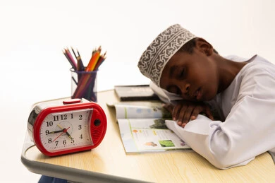 طفل عُماني نائم على المكتب أثناء المذاكرة