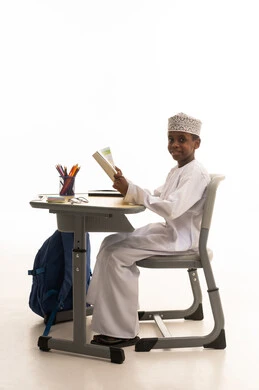 طالب عماني يقرأ على مقعد مدرسي خلفية بيضاء