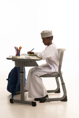 طالب عماني يكتب على مقعد دراسي بخلفية بيضاء