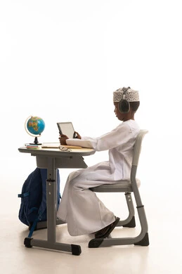 طالب عماني يستخدم الجهاز اللوحي في مقعد دراسي