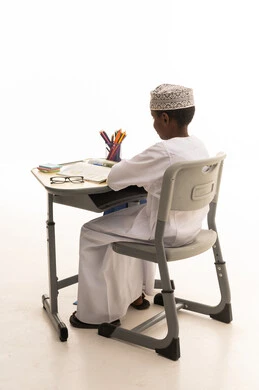 طالب عماني يجلس على مقعد دراسي في الاستوديو