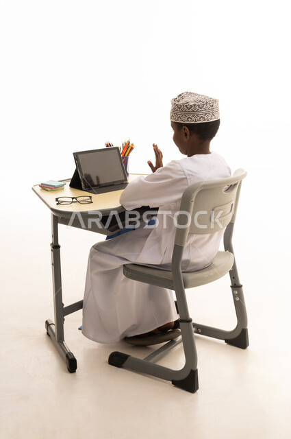 Omani Boy Using Tablet for Online Learning at Desk