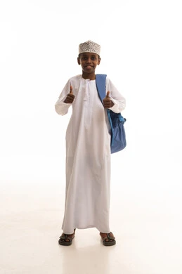 طفل عماني بالزي التقليدي مع حقيبة مدرسية