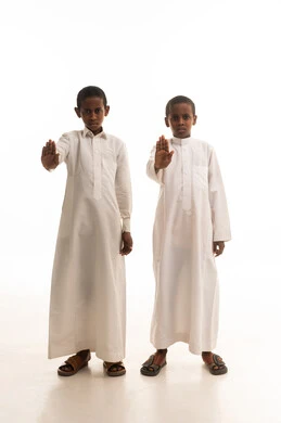 طفلان بالثوب الأبيض يقومان بإيماءة التوقف