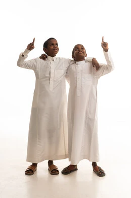 أطفال سعوديون بالثوب الأبيض يشيرون للأعلى في الاستوديو