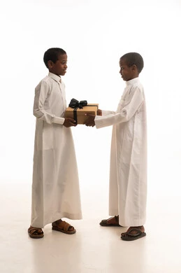 طفلان بملابس تقليدية سعودية يتبادلان الهدايا في استوديو