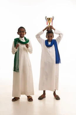 Boys in Traditional Thobes Celebrating with Gold Trophy