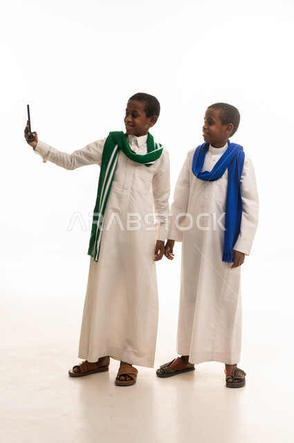Saudi Boys in Traditional Thobes Using Smartphone Studio