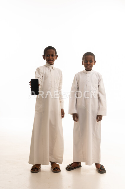Saudi Boys in Traditional Thobes Holding Smartphone