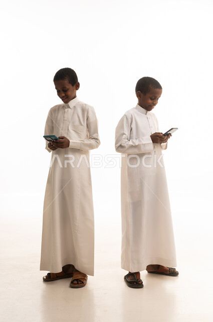 أطفال سعوديون بالثوب الأبيض يستخدمون الهواتف الذكية