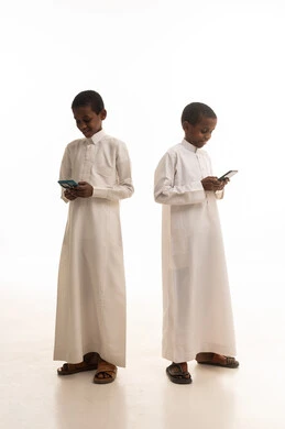 أطفال سعوديون بالثوب الأبيض يستخدمون الهواتف الذكية