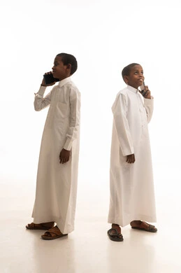 أطفال سعوديون بالثياب التقليدية يستخدمون الهواتف المحمولة