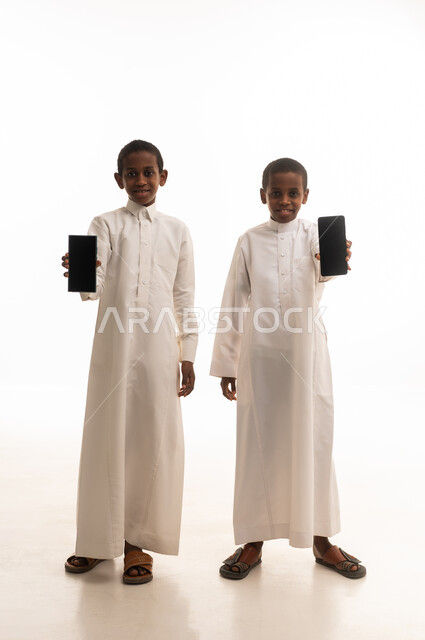 Saudi Boys in Traditional Thobes Holding Smartphones