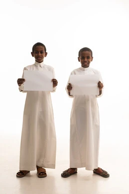 أطفال سعوديون بالثوب التقليدي يحملون أوراقاً بيضاء