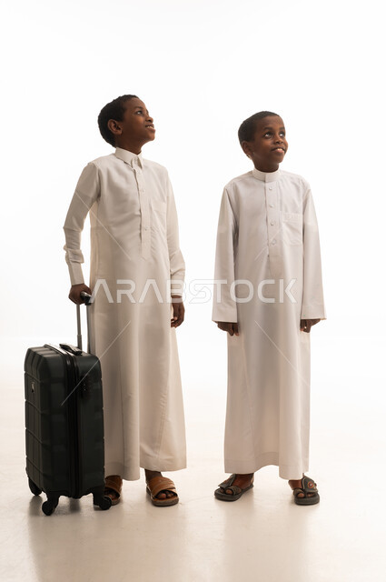 أطفال سعوديون بالثوب التقليدي مع حقيبة سفر سوداء