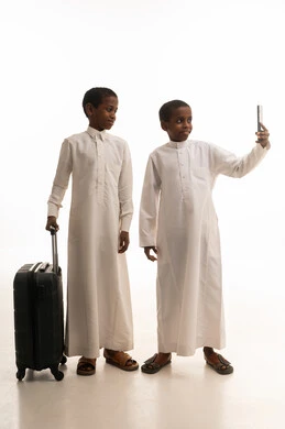 أطفال سعوديون بالثوب مع حقيبة سفر وصورة سيلفي
