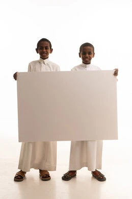 أطفال سعوديون يحملون لوحة إعلانية بيضاء فارغة