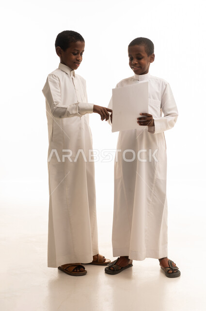 Saudi Boys in Traditional Thobes Holding White Paper