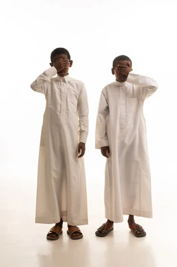 طفلان يرتديان الثوب الأبيض التقليدي بخلفية بيضاء