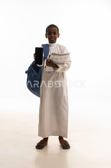 طالب سعودي يحمل هاتف ذكي وحقيبة مدرسية