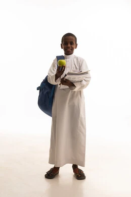 طالب سعودي يحمل تفاحة وكتباً بخلفية بيضاء