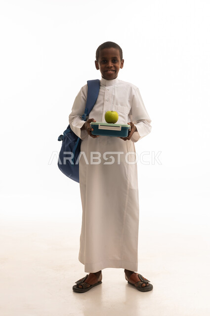 طالب سعودي بالثوب يحمل صندوق غداء وتفاحة