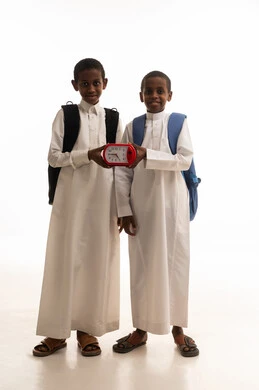 طلاب سعوديون يحملون ساعة منبه بخلفية بيضاء