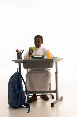 طالب سعودي خلف المكتب مع وجبة صحية