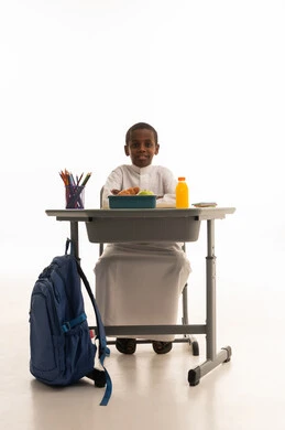 Saudi Schoolboy at Desk with Lunch on White Background