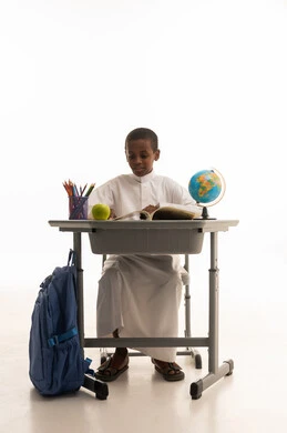 طالب سعودي يرتدي الثوب يجلس على مقعد دراسي