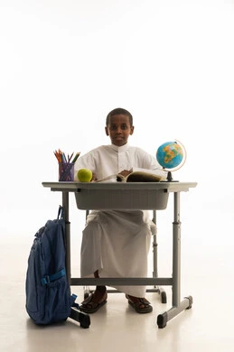 طالب مدرسة أفريقي بالثوب الأبيض على المقعد الدراسي