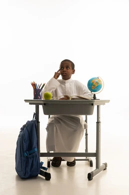 طالب سعودي يفكر خلف مقعده الدراسي في الاستوديو