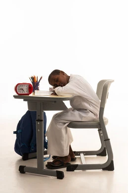 African Student Sleeping on Desk with Clock