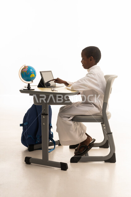 Young Student in Thobe Using Tablet at School Desk