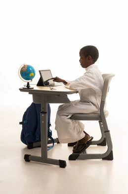 Young Student in Thobe Using Tablet at School Desk