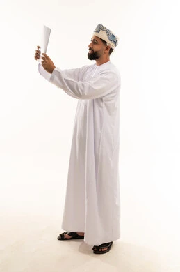 رجل عُماني بالزي التقليدي يقرأ وثيقة ورقية