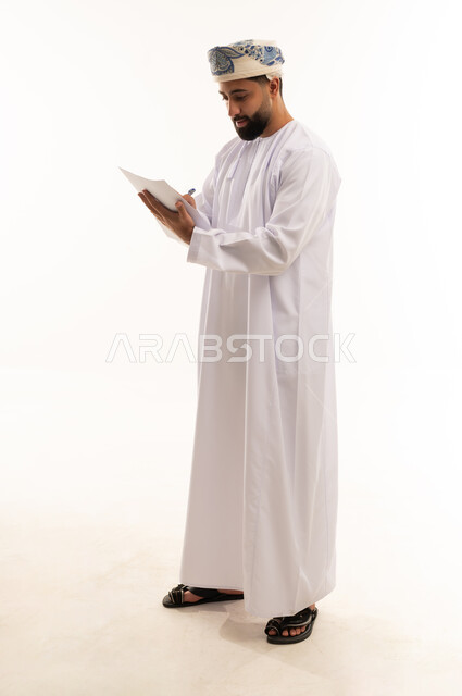 رجل عماني بالزي التقليدي يكتب على ورق