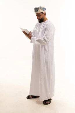 رجل عماني بالزي التقليدي يكتب على ورق