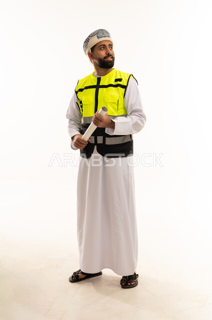 مهندس عماني يحمل مخطط هندسي بسترة السلامة